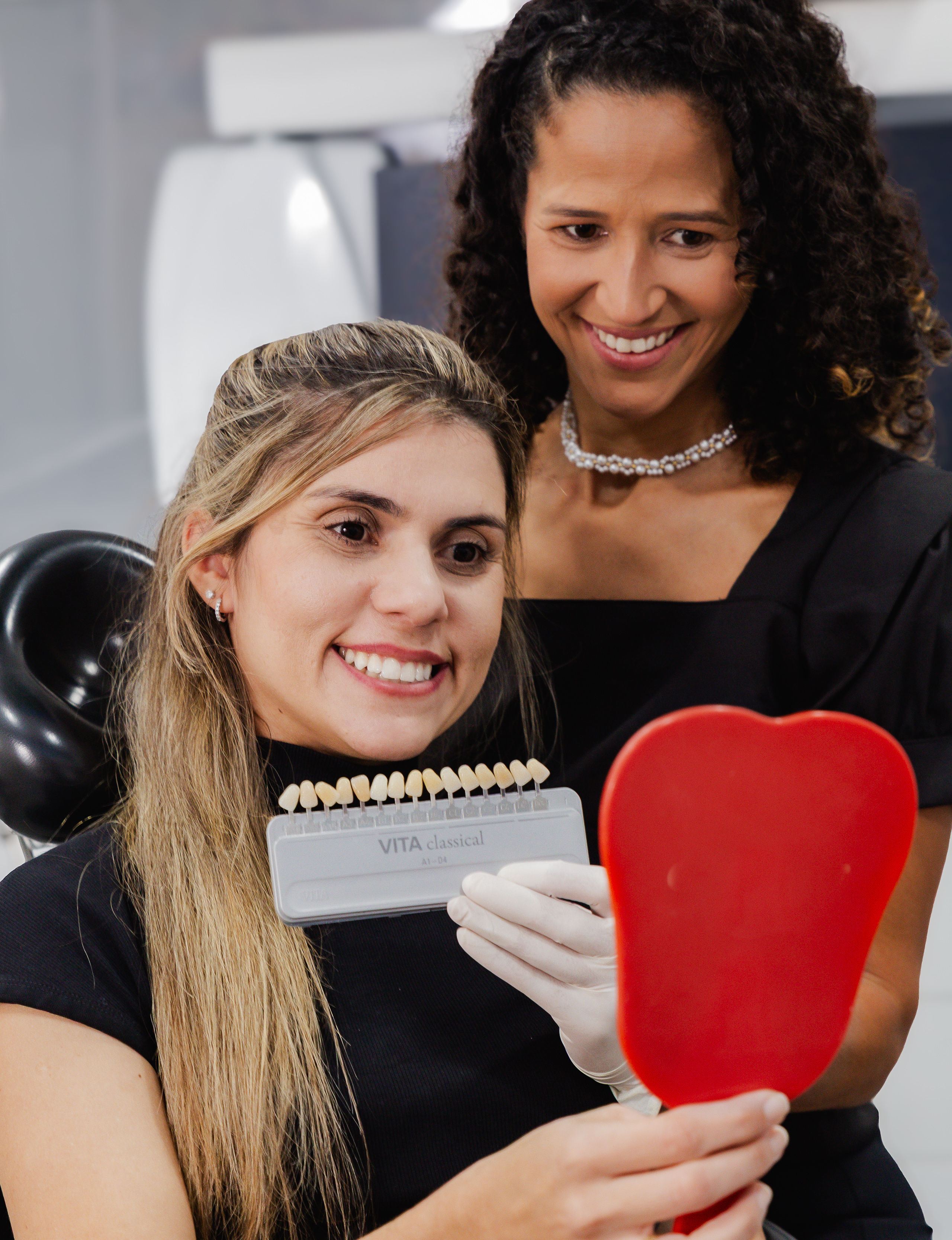 Patient viewing her new smile with a mirror and shade guide